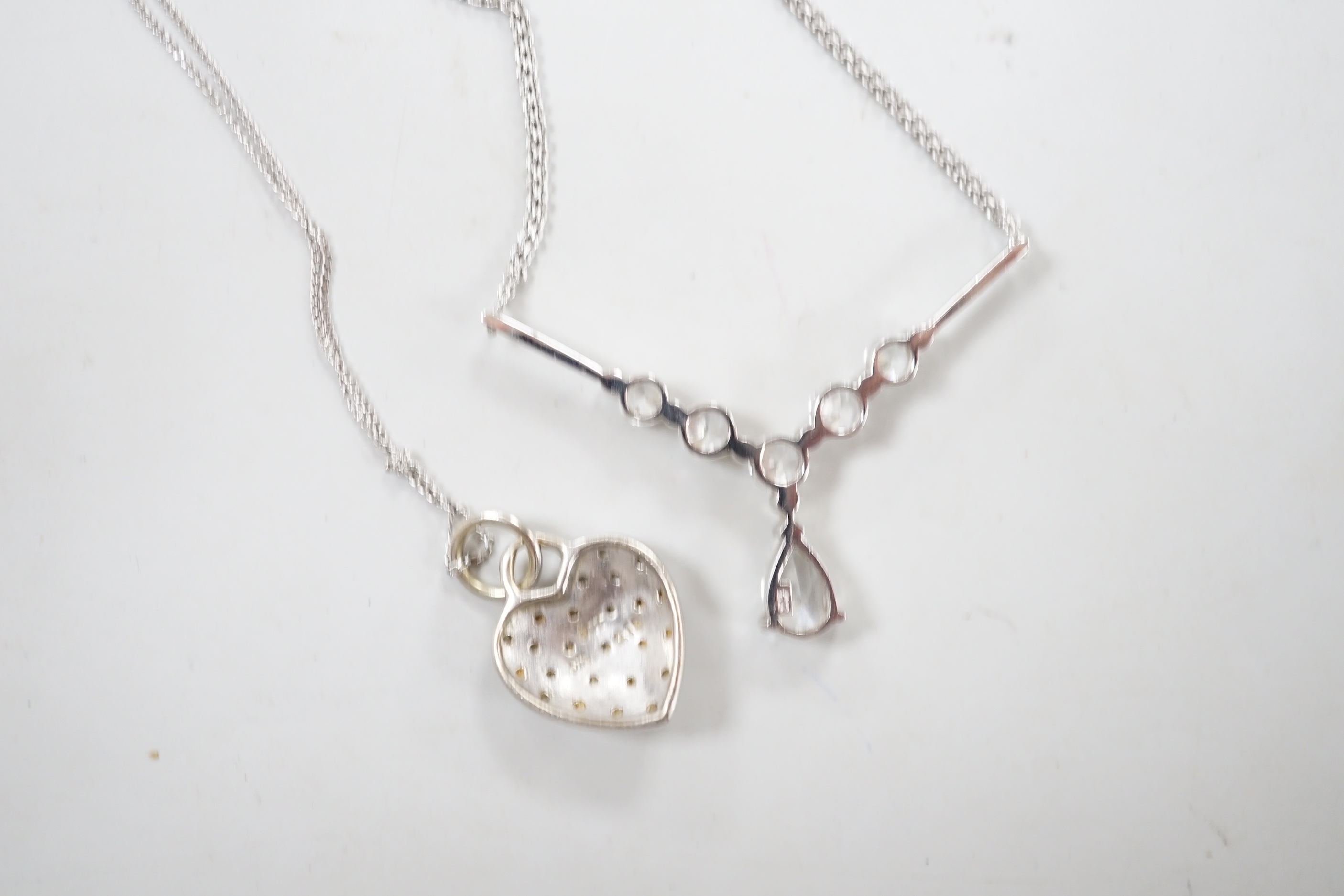 Two modern white metal (stamped 375) and gem set pendant necklaces, including a diamond chip set heart, longest 50cm